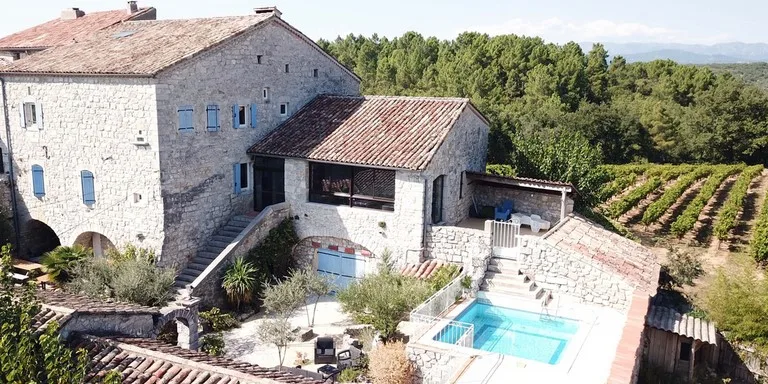 Vue aérienne du grand mas en pierre avec sa cour, son terrain et son environnement de collines