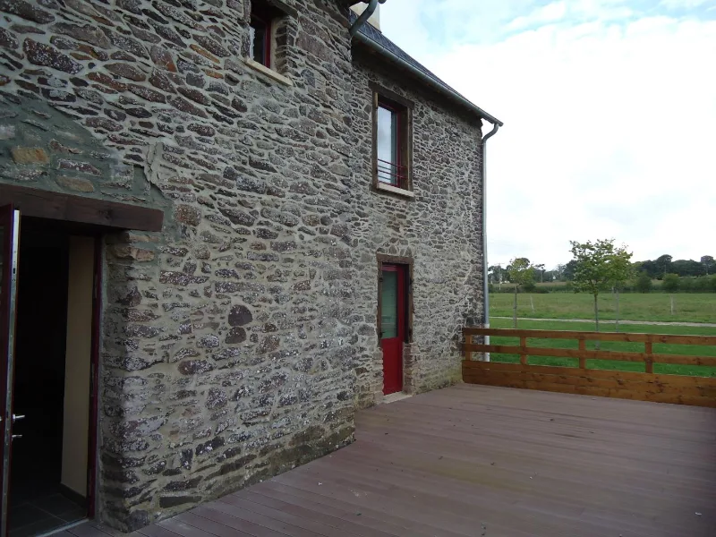 Mur en pierre ancien et terrasse en bois à l'arrière du manoir