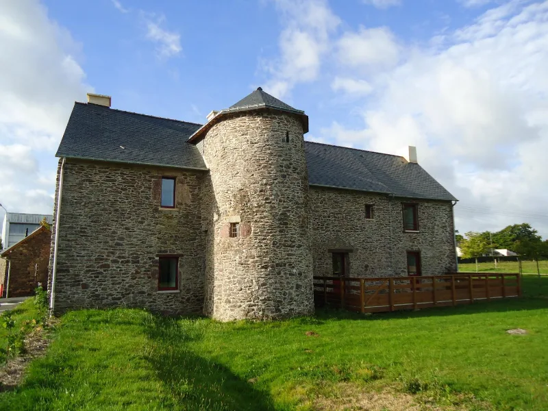 Façade en pierre du manoir avec sa tour ronde et son toit d'ardoise