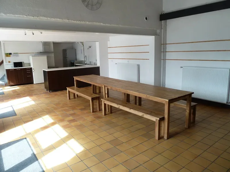 Grande salle polyvalente aménageable avec mobilier léger pour repas et réunions de groupe