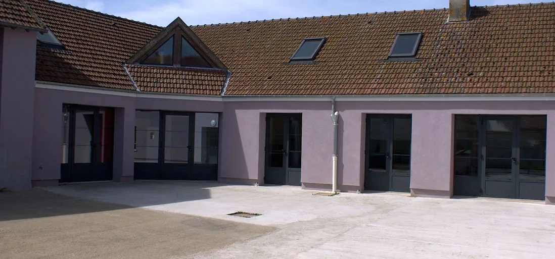 Gîte de groupe Gîte de Groupes des Foyers Ruraux à Nucourt — Façade en U du gîte de groupe de Nucourt avec cour intérieure pavée et toiture en tuiles, capacité 14 personnes