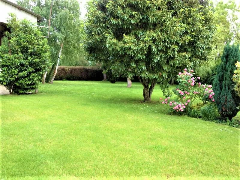 Jardin arboré et pelouse verdoyante bordée de massifs fleuris