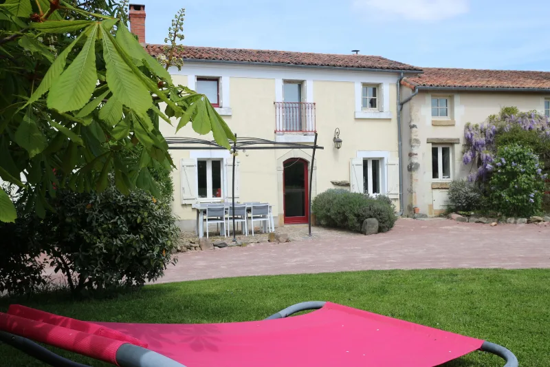 Façade arrière et jardin avec terrasse, table extérieure et pelouse ombragée