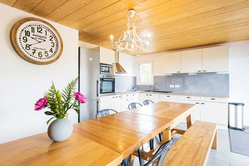 Cuisine équipée et table conviviale sous plafond en bois