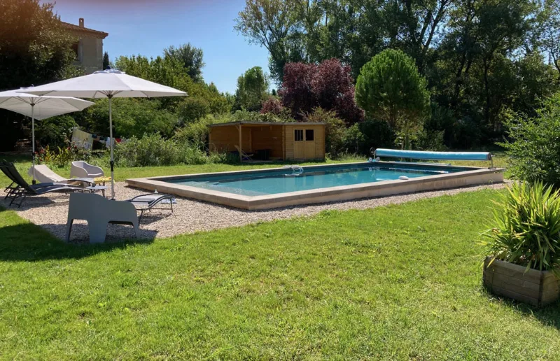 Piscine de 5x11 m avec pelouse et transats devant le mas en pierre