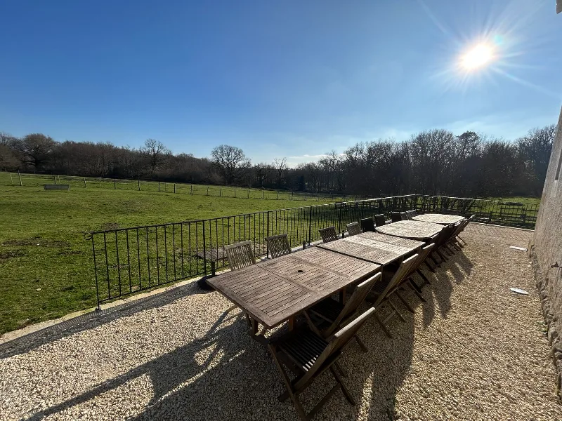 Grande terrasse extérieure avec table en bois dressée pour un repas de groupe