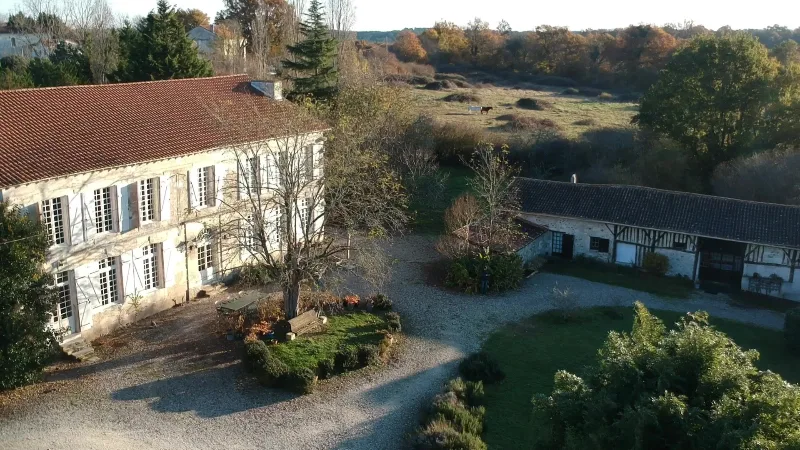 Vue aérienne de la façade en pierre du château avec toiture de tuiles et parc arboré