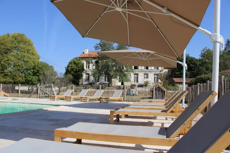Piscine extérieure avec transats et vue sur la façade du château au fond