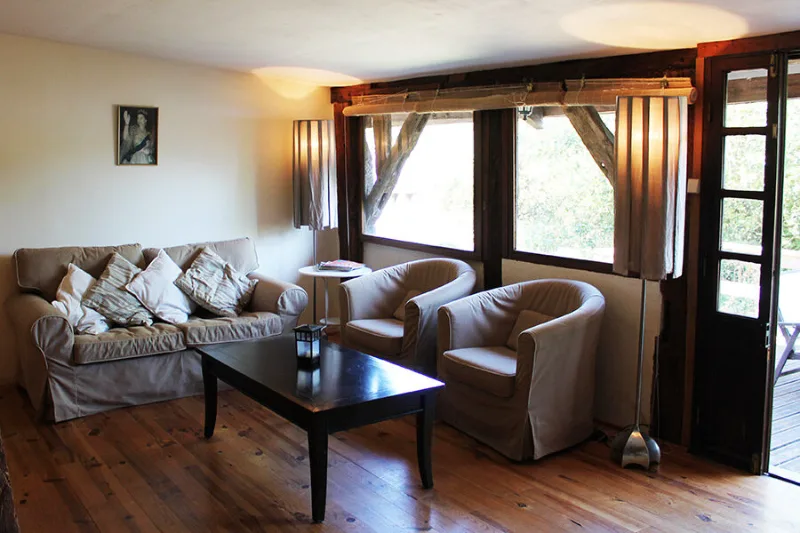Salon lumineux avec canapé, fauteuils et porte-fenêtre donnant sur l'extérieur