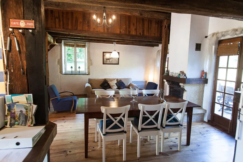 Salon cosy avec cheminée, fauteuils et poutres en bois apparentes