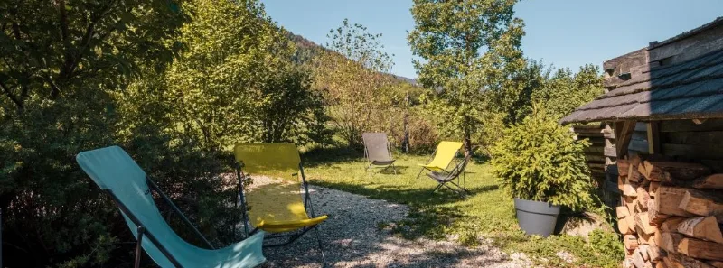 Terrasse ombragée du gîte Lanchette avec tables et chaises en bois pour les repas