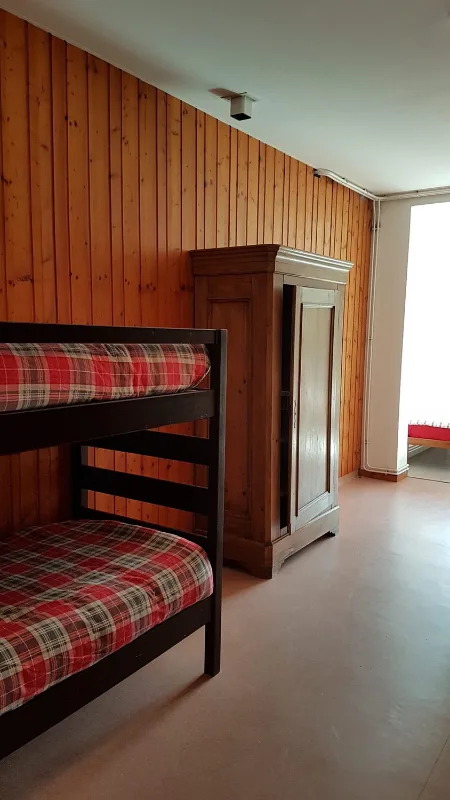 Chambre avec lits superposés en bois et armoire ancienne