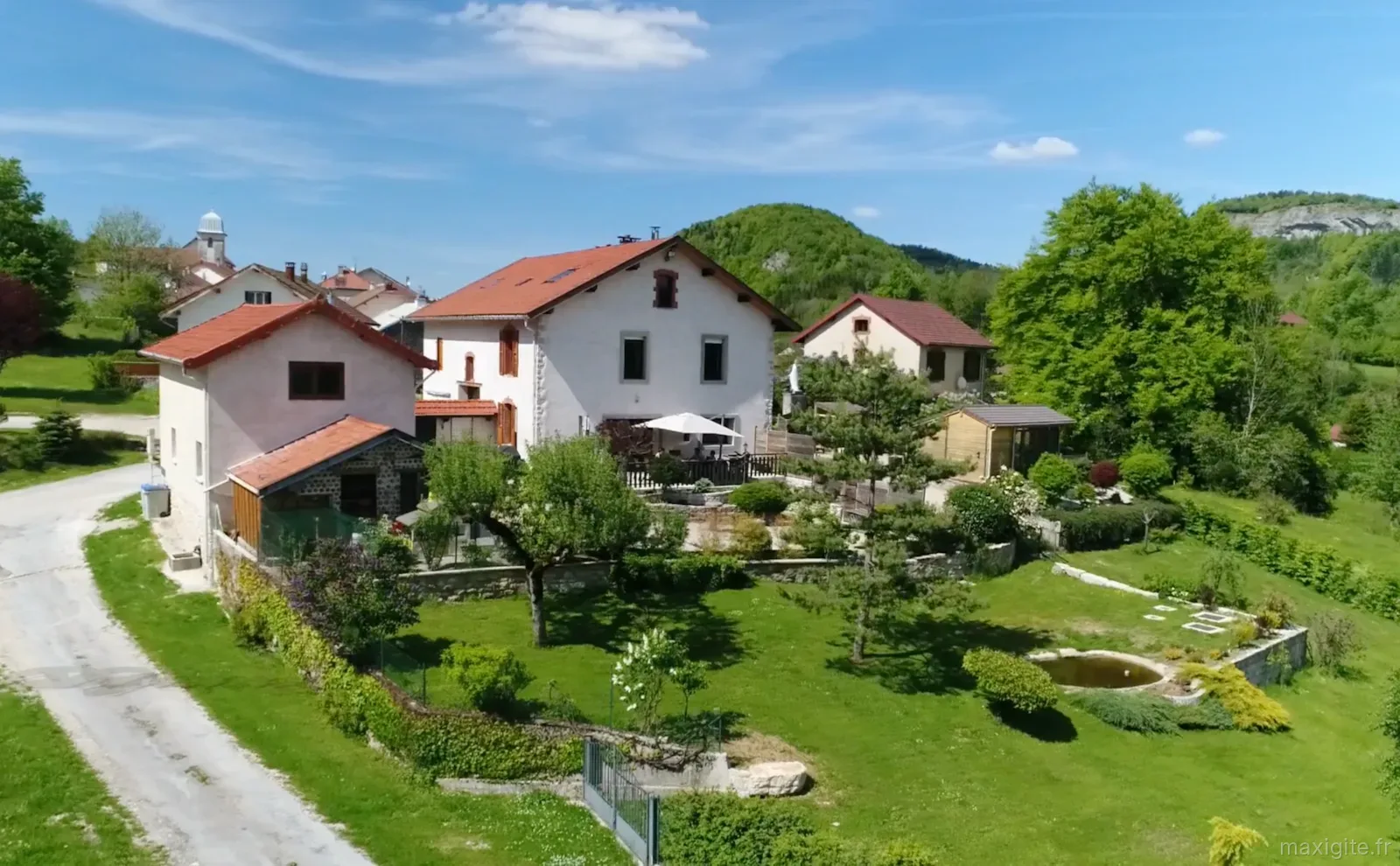Gîte de groupe Gite des Monts Jura à Les Crozets — Vue aérienne du gîte des Monts Jura entouré de verdure dans le village des Crozets, capacité 14 personnes