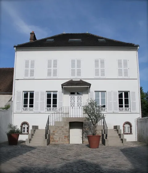 Façade principale de la villa depuis la cour pavée avec perron d'entrée