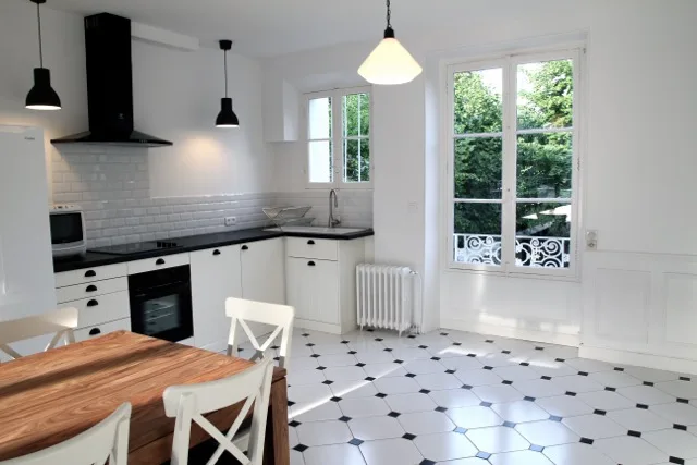 Cuisine équipée avec îlot central et grande fenêtre sur le jardin