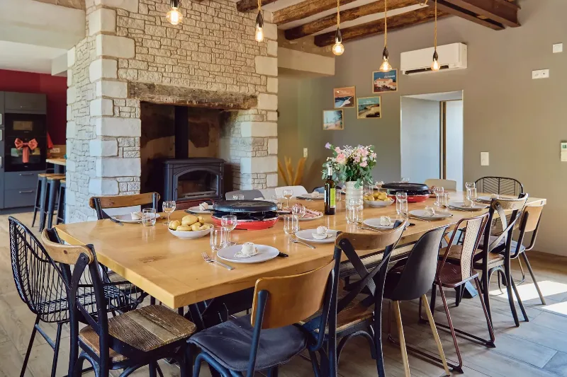 Grande salle à manger avec cheminée en pierre et poutres apparentes