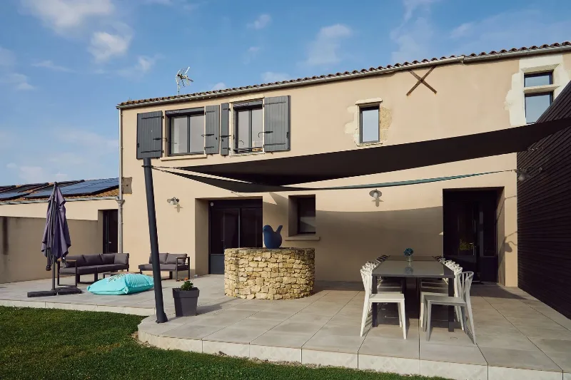Terrasse extérieure avec grande table à manger et voile d'ombrage