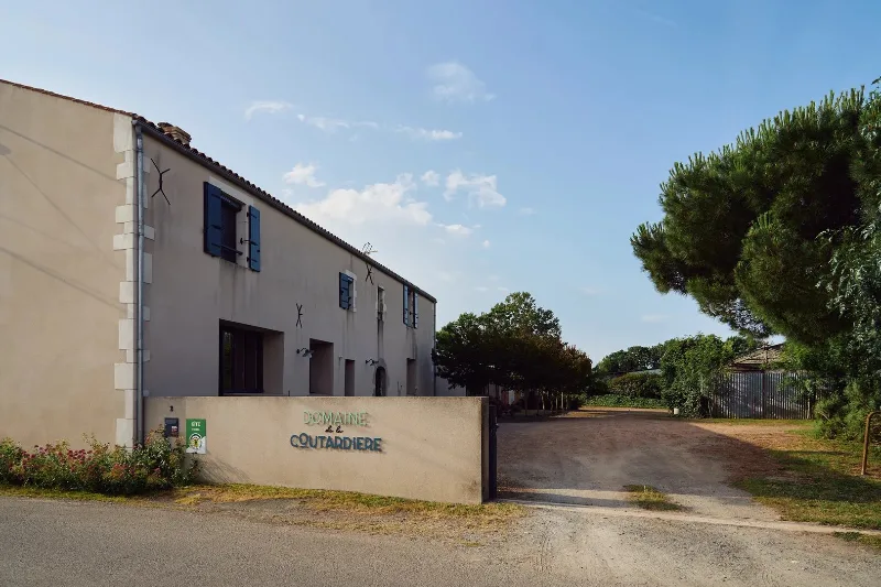 Façade en pierre du Domaine de la Coutardière avec enseigne et volets bleus