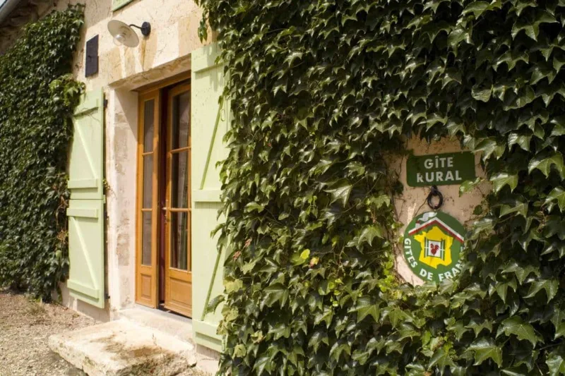 Cour extérieure du gîte du Tremblay avec façade en pierre des anciennes écuries