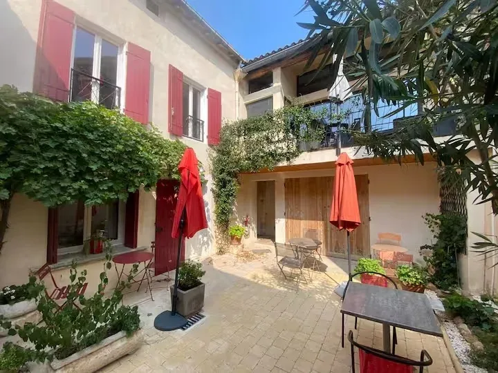 Façade du mas provençal avec volets rouges, cour intérieure pavée et terrasses