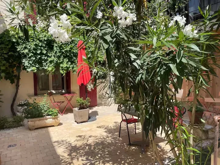 Cour intérieure ombragée avec tables, chaises et parasols rouges pour profiter en extérieur