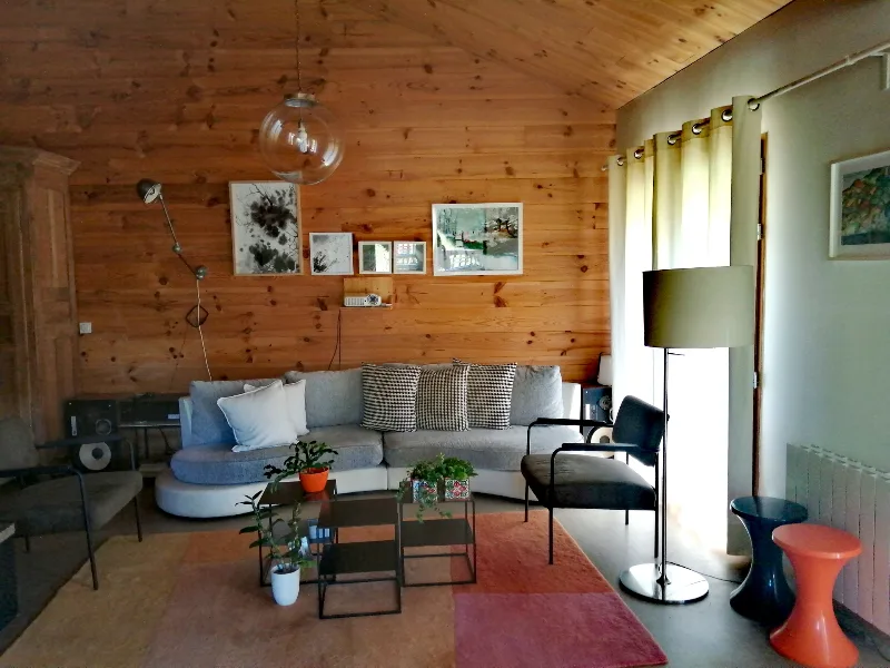 Grand salon lambrissé en bois avec canapés et coin lecture