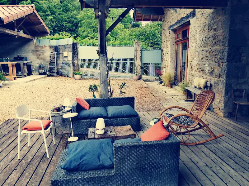 Terrasse extérieure avec salon de jardin et coin détente face à la cour