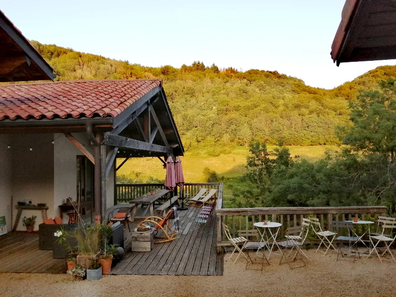 Terrasse en bois du gîte avec vue panoramique sur la vallée boisée du Bugey