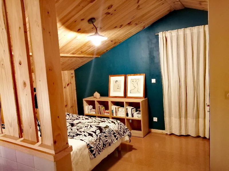 Chambre mansardée avec lit double sous charpente en bois