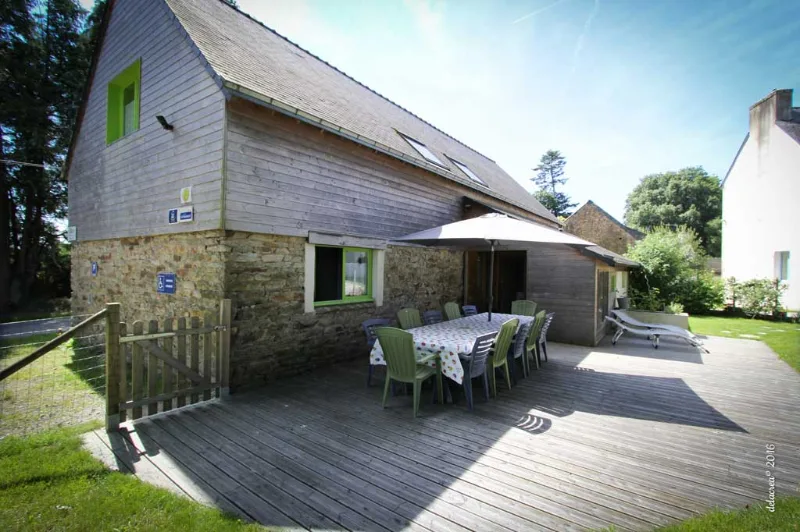 Terrasse en bois avec table de jardin et parasol, façade pierre et bois