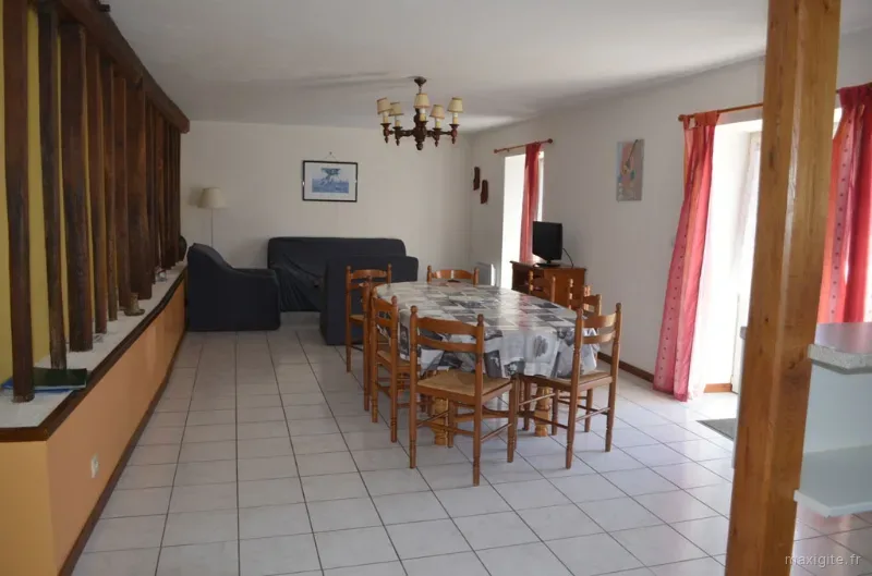 Salon avec canapés et grande table à manger en bois pour les repas de groupe