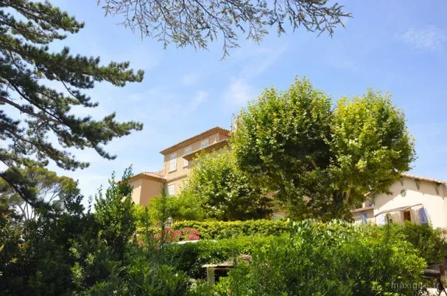 Gîte de groupe La Bastide des Escourches à Marseille — Salle à manger avec plusieurs tables dressées et cheminée en pierre, capacité 30 personnes