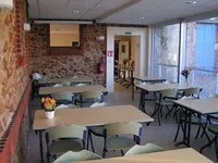 Salle de restauration avec tables et bancs, murs en brique apparente