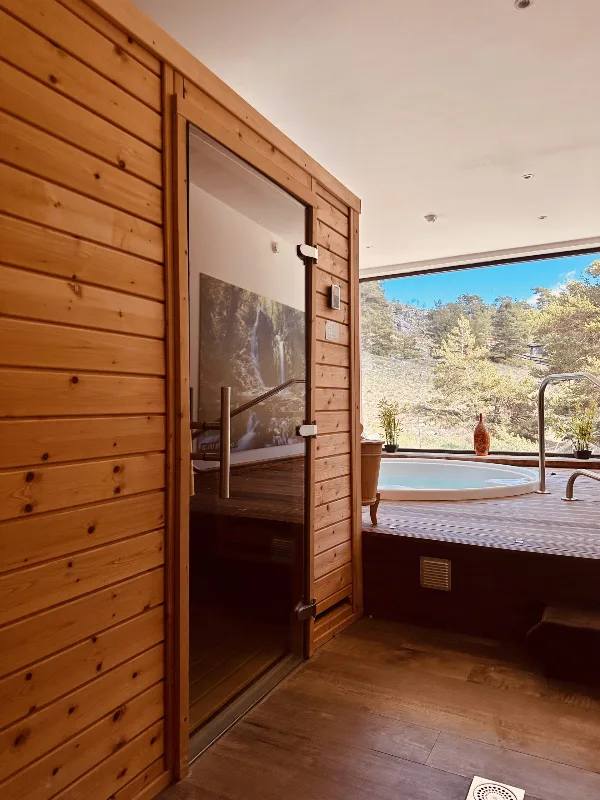 Espace bien-être avec sauna nordique en bois et jacuzzi extérieur vue sur la montagne