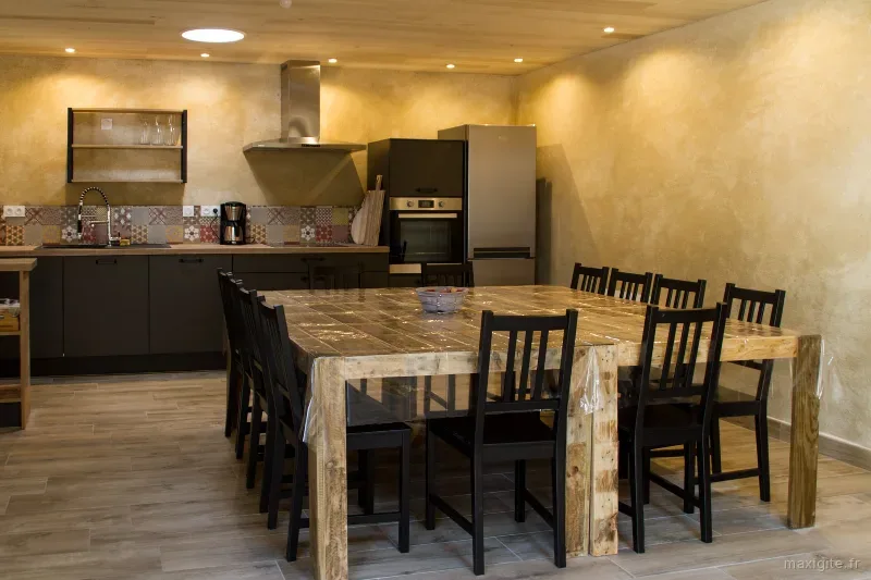 Cuisine équipée avec table en bois et chaises pour les repas de groupe