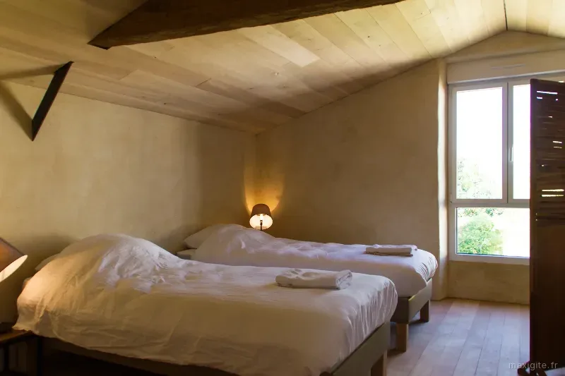 Chambre mansardée avec lit double et petite fenêtre sous les combles