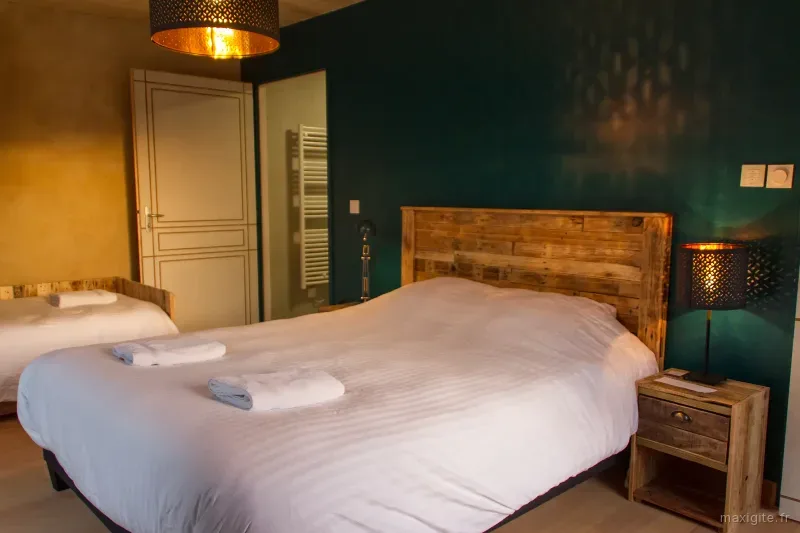 Chambre double avec tête de lit en bois et mur vert foncé