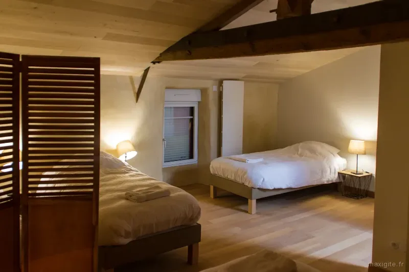 Chambre lumineuse avec deux lits et volets en bois