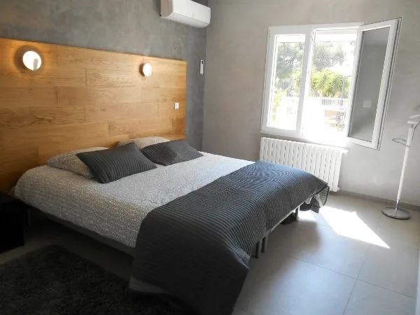 Chambre double avec tête de lit en bois et climatisation