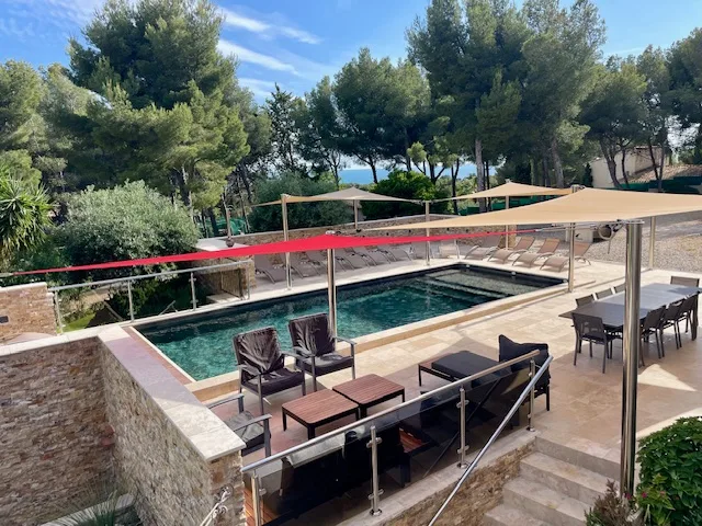 Piscine chauffée et terrasse avec salon extérieur, entourée de pins