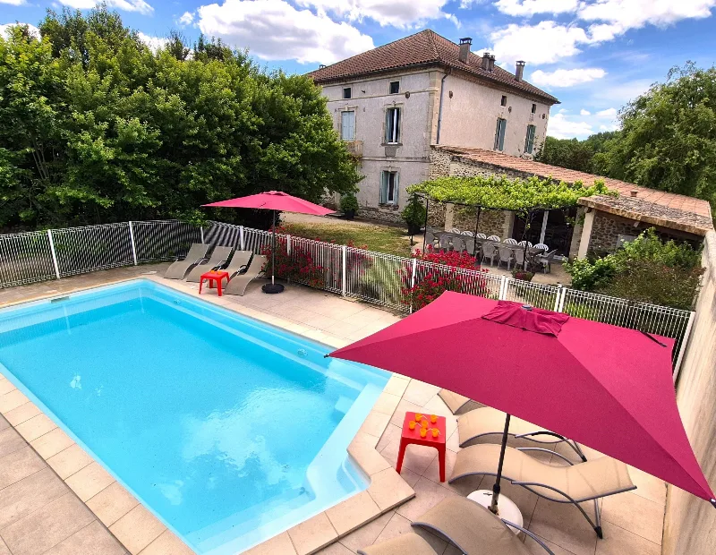 Piscine clôturée avec transats et grande terrasse dominant le jardin et la maison