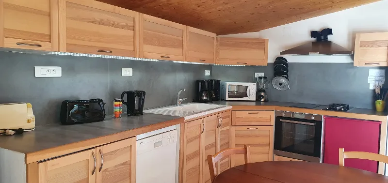 Cuisine équipée en bois avec lave-vaisselle, four, plaques de cuisson et grand plan de travail