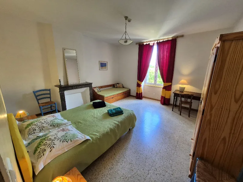Chambre lumineuse avec lit double, cheminée en marbre et grande armoire en bois