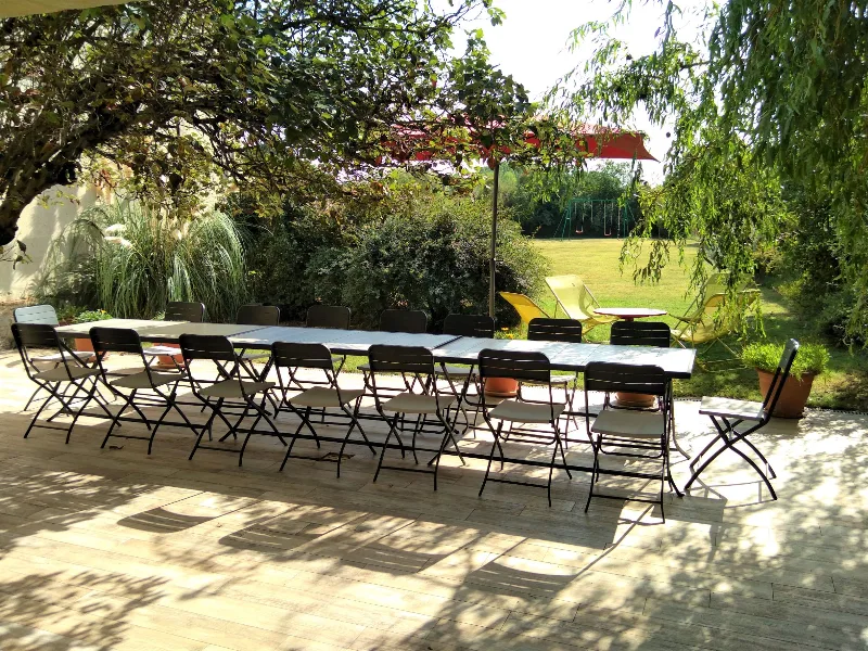 Terrasse ombragée sous treille avec longue tablée pour les repas de groupe et vue sur le parc