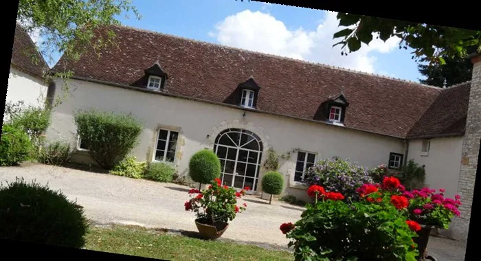 Gîte de groupe Gîte de la Vergne à Lunery — Façade en pierre du domaine avec toiture de tuiles et jardin fleuri à l'entrée, capacité 17 personnes