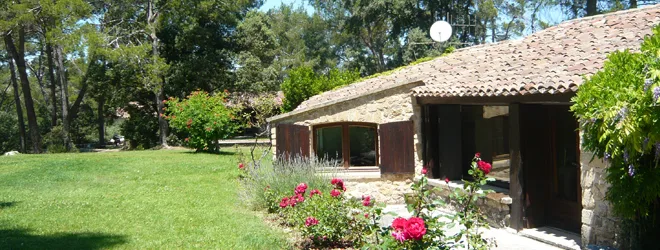 Gîte de groupe Le Jas de Mathurin à Peyrolles-en-Provence — Façade en pierre du Jas avec toiture de tuiles et jardin fleuri de rosiers, capacité 17 personnes