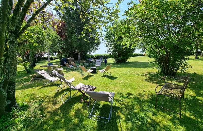 Coin détente ombragé sous les arbres avec chaises longues et table de jardin