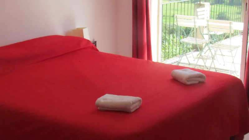 U Pianarellu – OlmetoChambre avec lit double, couvre-lit rouge et accès à un balcon