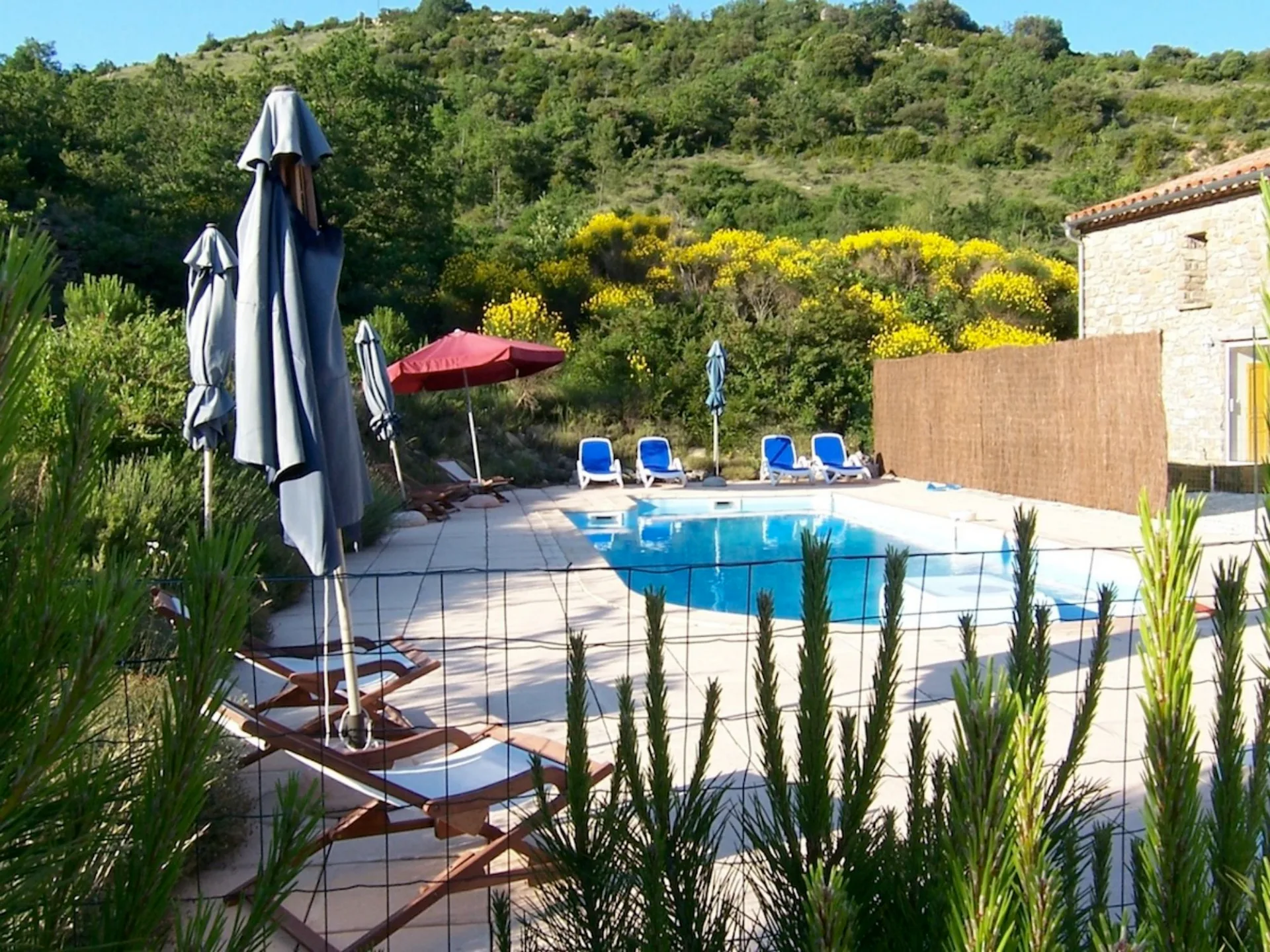 Gîte de groupe Les Gîtes du Torgan à Massac — Les Gîtes du Torgan – MassacPiscine entourée de transats et parasols, au coeur de la garrigue avec bâtiment en pierre, capacité 45 personnes