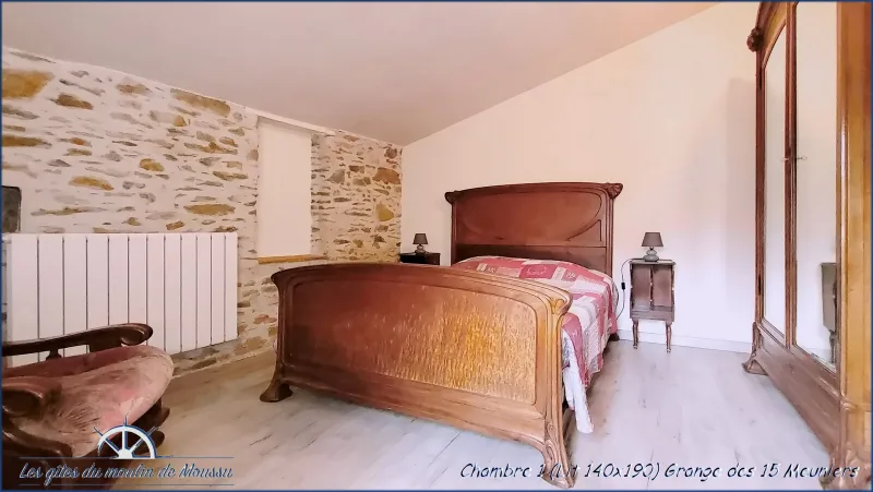 Chambre avec lit ancien en bois sculpté et mur en pierre apparente